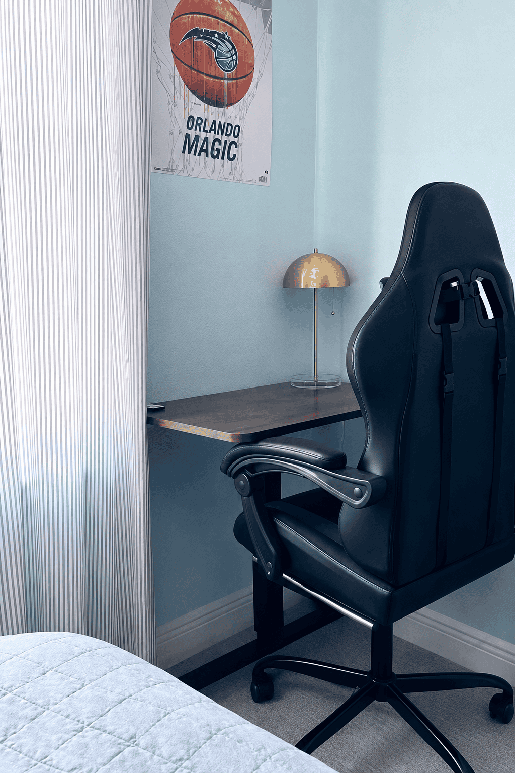 Home office with black ergonomic chair, desk, and Orlando Magic poster.