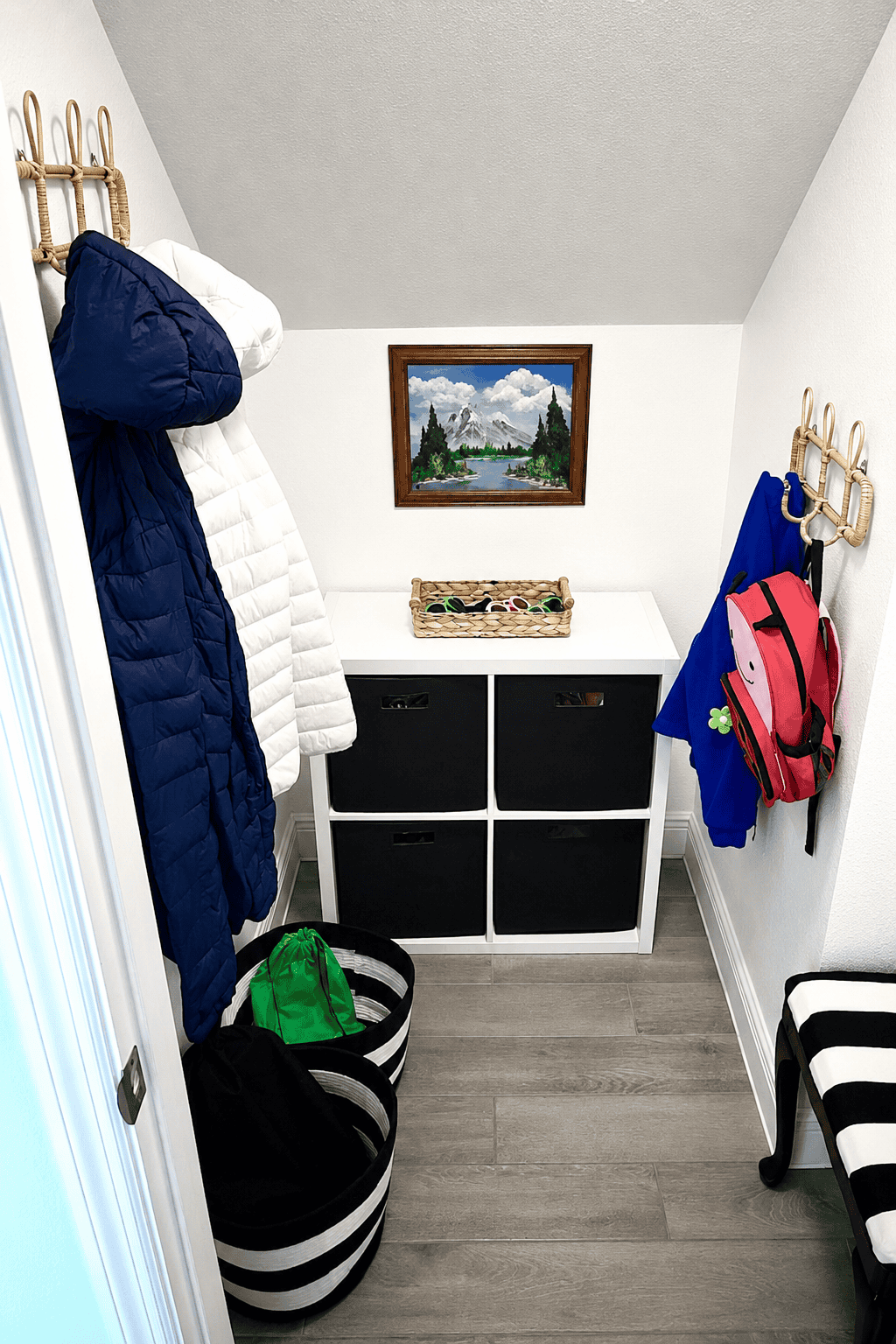 Cozy mudroom with coat hooks, storage bench, and decorative painting.