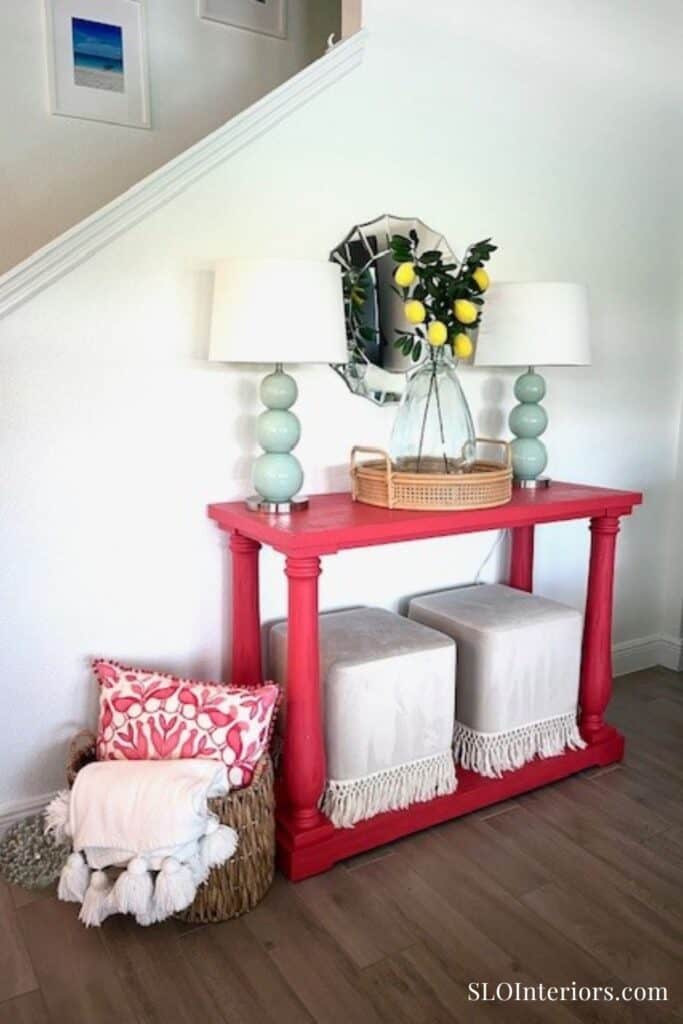 Bright entryway with pink console table, lamps, and decorative mirror with lemons.