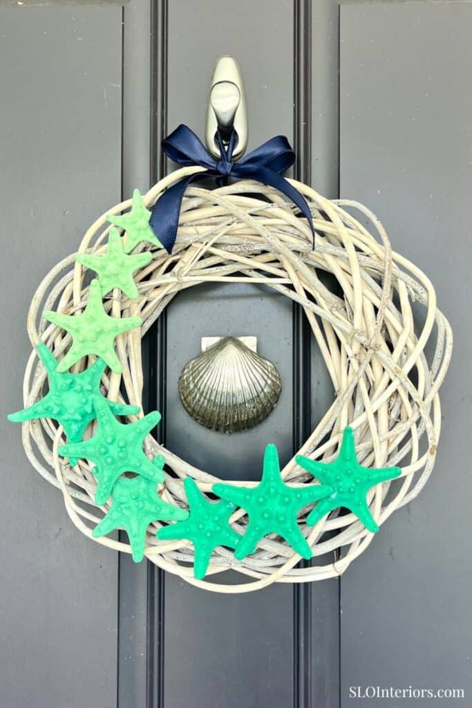 Decorative wreath with starfish and seashell on a gray door.