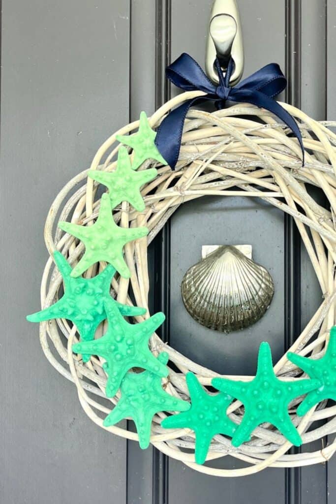 Beach-themed wreath with starfish and seashell decorations for coastal decor.