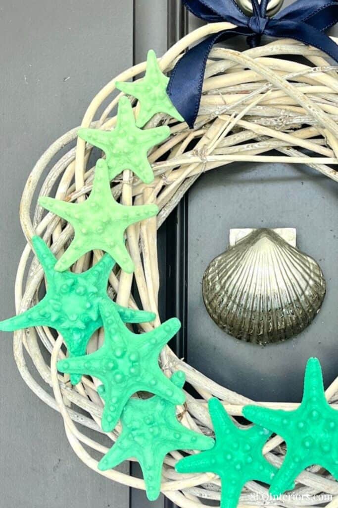 Decorative starfish-shaped ornaments on a wicker mirror frame with a shell in the background.