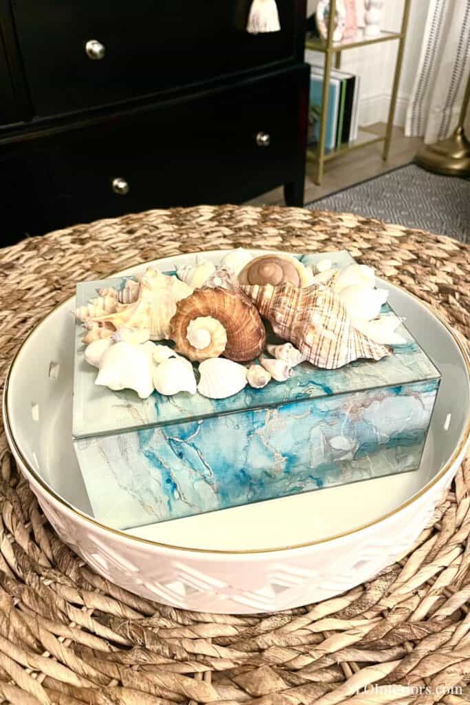 Decorative seashells on a glass and marble tray in coastal-themed decor.
