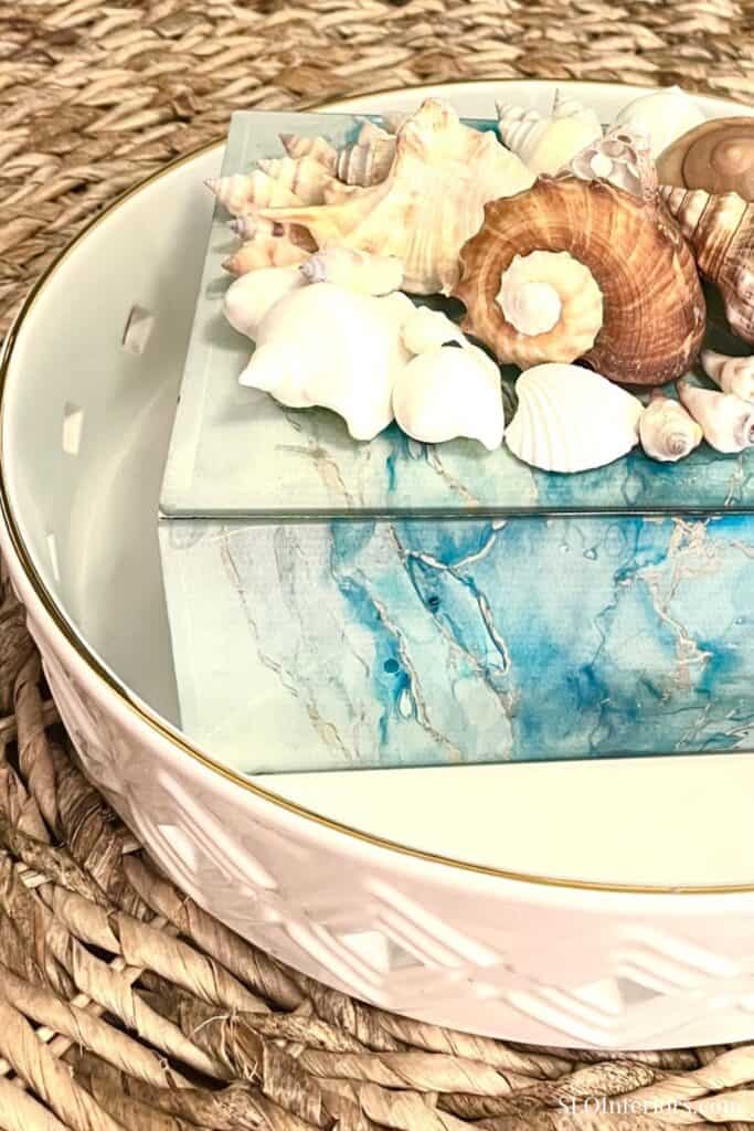 Decorative seashells on a blue marble-patterned box with a woven background.