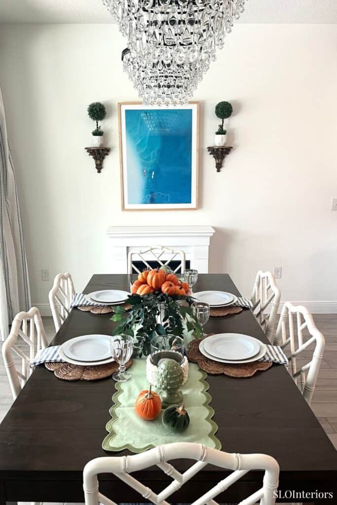 Elegant dining room with chandelier, white walls, and autumn-themed table setting.