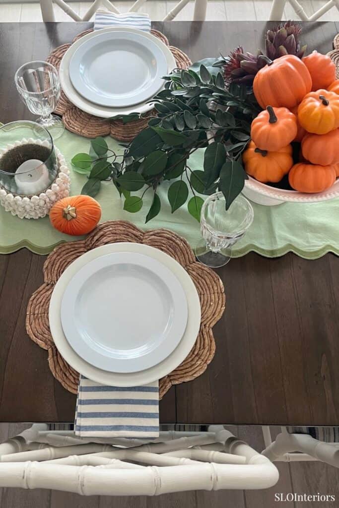 Fall-themed table setting with pumpkins, greenery, and autumn decor.