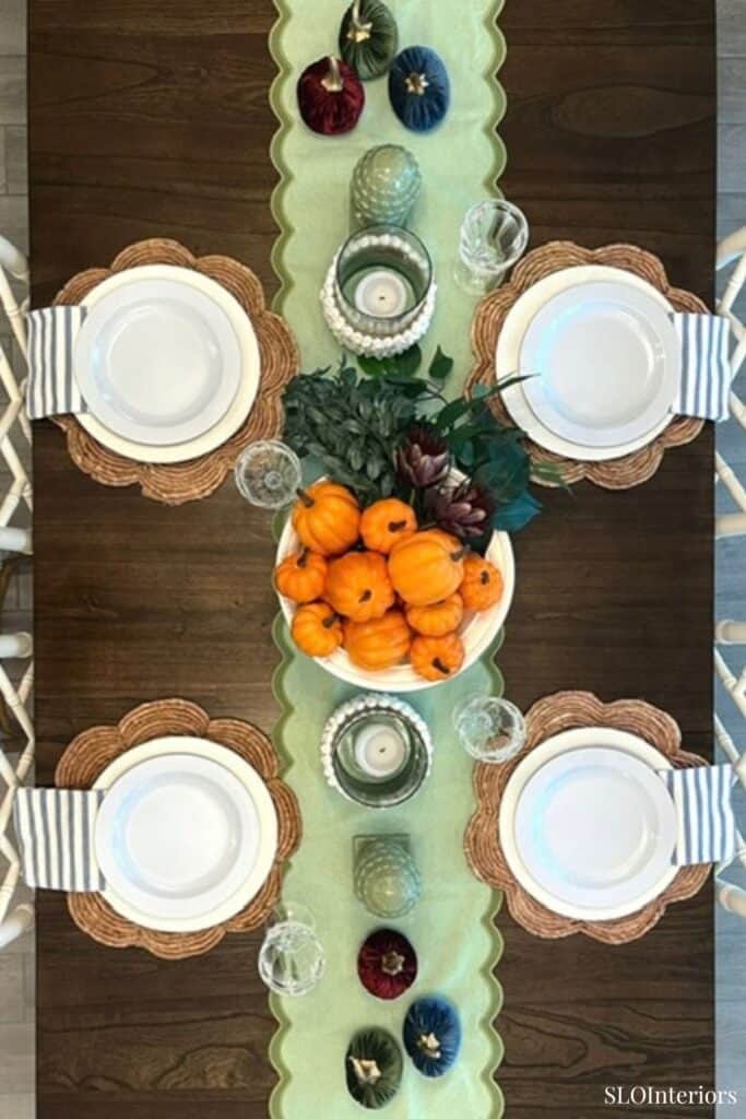 Elegant fall table setting with pumpkins, candles, and decorative gourds for autumn decor.