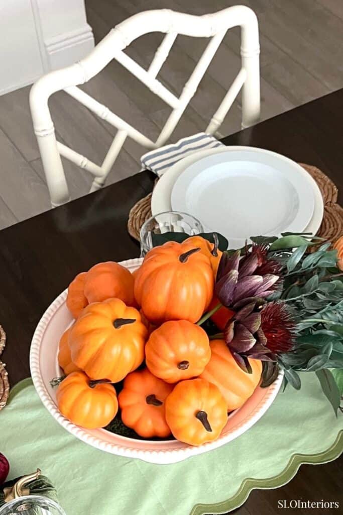 Decorative autumnal table setting with mini pumpkins and flowers for fall decor.
