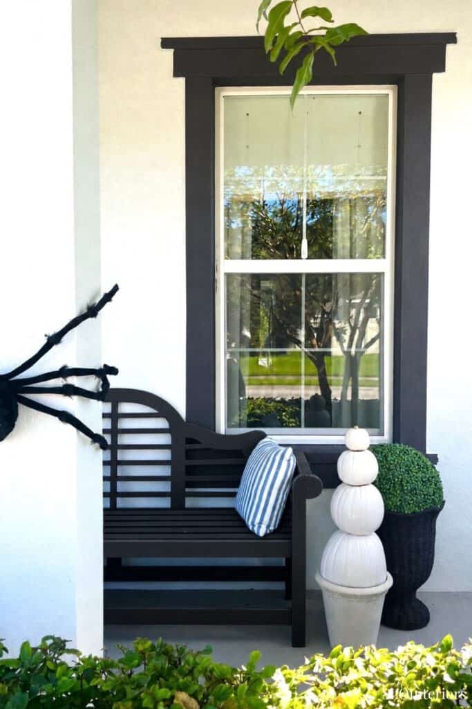 Charming outdoor porch with black bench, window, and decorative planters.