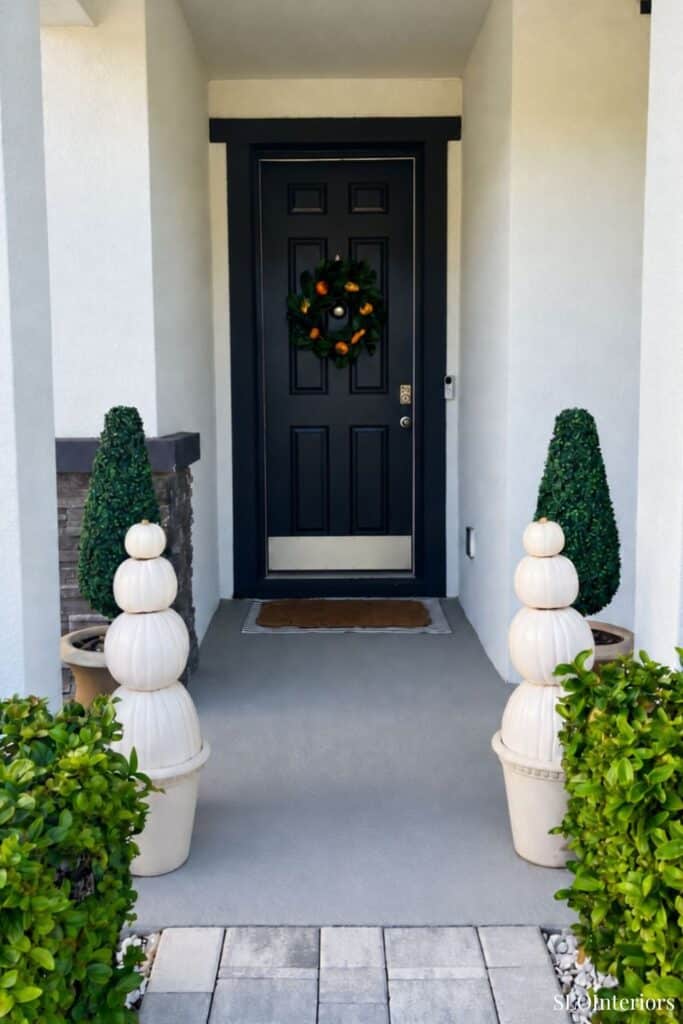 Front door decorated with a festive wreath and potted plants for holiday decor.