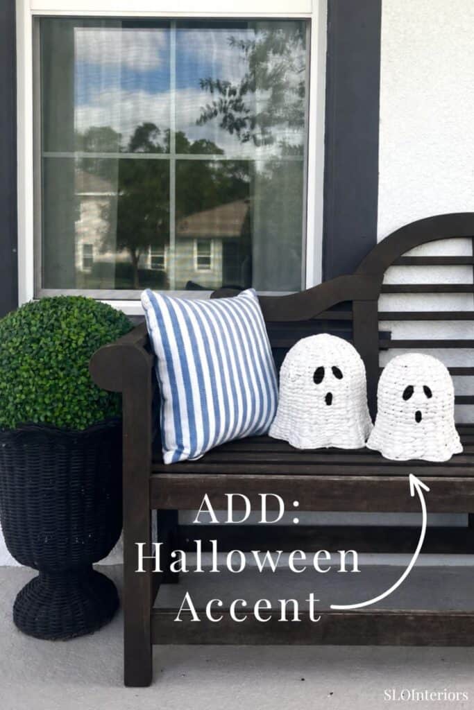 Decorative Halloween ghost accents on outdoor bench with striped pillow and potted plant.