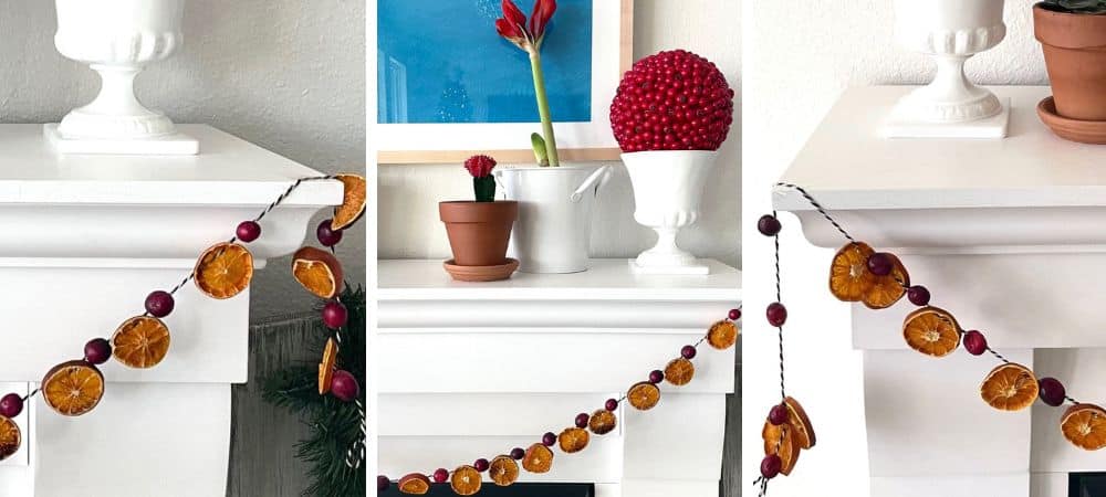 A festive holiday garland with dried orange slices and berries on a white mantelpiece.