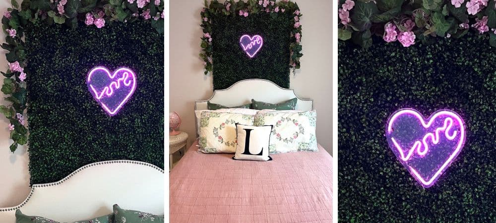 Decorative bedroom wall with neon heart and love sign, floral backdrop, and cozy bedding.